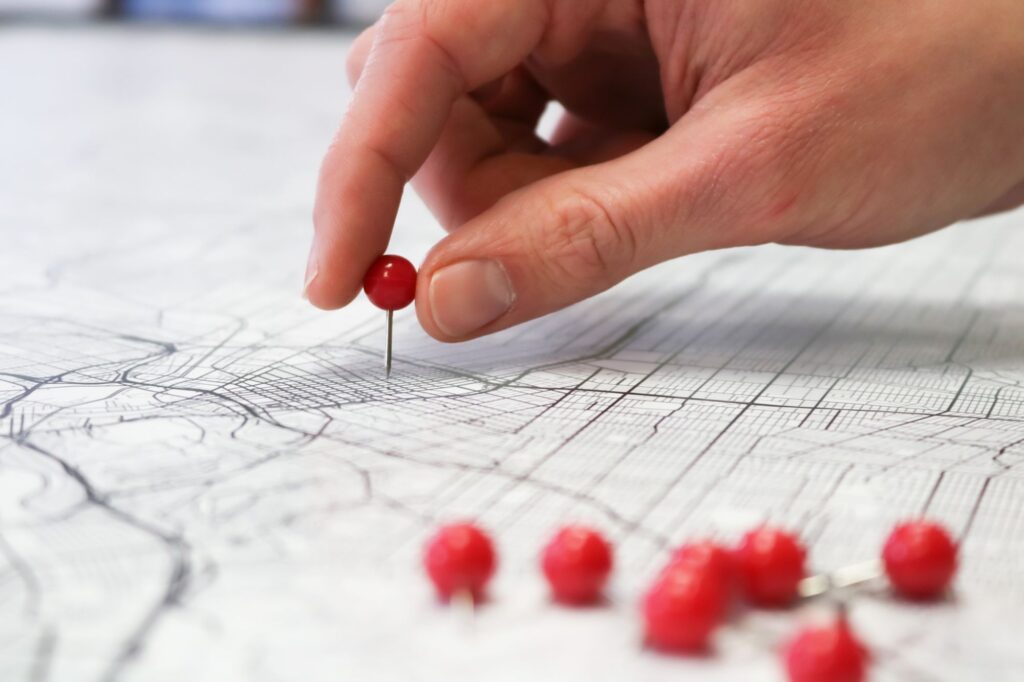 Hand placing a pin on a map to plan a sales territory